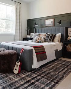 a bedroom with a guitar on the floor next to a large bed and rugs