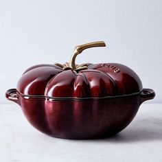 a red casserole dish sitting on top of a white countertop next to a wall