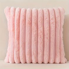 pink pillows stacked on top of each other in front of a white wall and floor