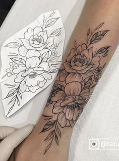 a woman's arm with flowers on it and a piece of paper next to it