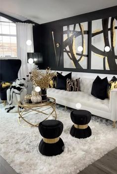 a living room with black and white furniture, gold accents and paintings on the wall