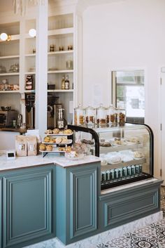 a bakery with blue cabinets and shelves filled with pastries, donuts and desserts