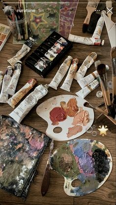 an artist's palette with paint, brushes and other art supplies on a table