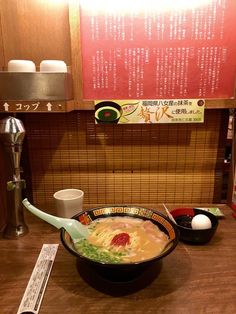 a bowl of soup with chopsticks in front of it on a wooden table