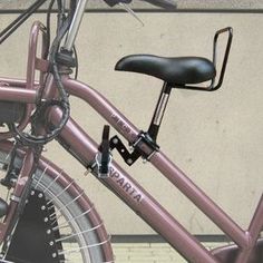 a pink bicycle parked next to a building