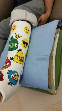 a man sitting on the floor with two pillows and one pillow that has angry birds on it