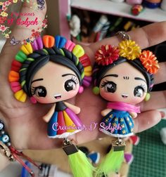 two little dolls that are sitting in someone's hand, one is wearing a colorful headdress