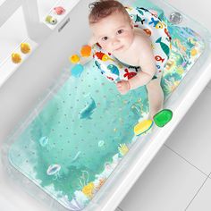 a baby laying in a bathtub on top of a tiled floor