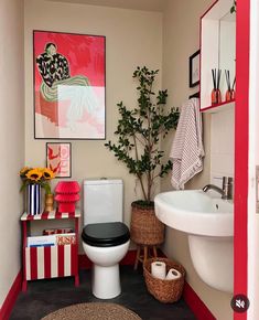 a bathroom with a toilet, sink and pictures on the wall