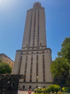 the tall building has many windows on it's sides and is surrounded by trees