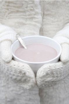 a person in white gloves holding a cup of hot chocolate