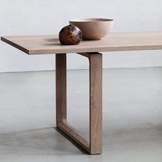 a wooden table with a bowl on it and a white wall in the back ground