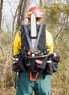 a man wearing a fireman's safety vest and helmet standing in the woods