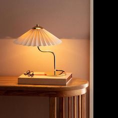 a table with a lamp on top of it next to a book and eyeglasses