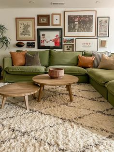 a living room with green couches and pictures on the wall above them, along with coffee table