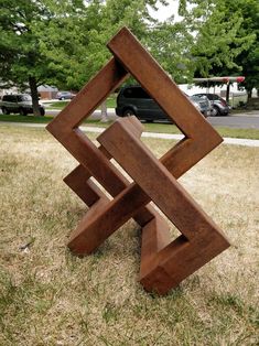 a wooden sculpture sitting on top of a grass covered field