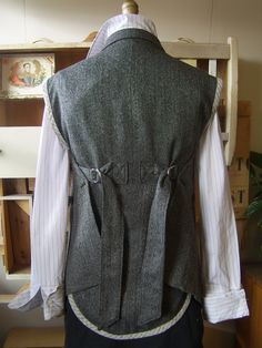 the back of a man's gray vest and white shirt