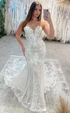 a woman taking a selfie while wearing a wedding dress in front of a store display