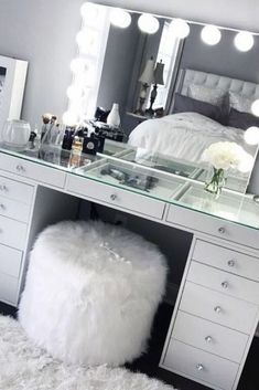 a bedroom with a vanity, mirror and stool on the floor in front of it