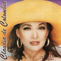 a woman wearing a large yellow hat and gold hoop earrings on her left hand, posing for the camera