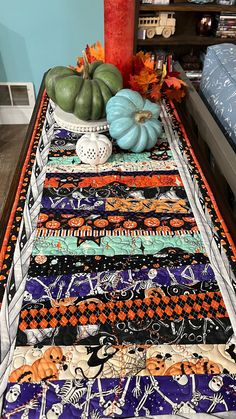 a table topped with lots of different types of quilts and pumpkins on top of it