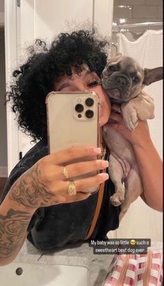 a woman taking a selfie with her cell phone while holding a small pug