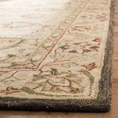 a close up of a rug on a wooden floor with a white and brown color scheme