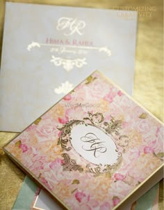 two wedding cards are sitting on top of each other and one has a monogrammed design