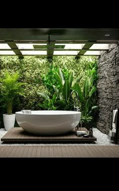 a bathtub in the middle of a bathroom with plants on the wall behind it