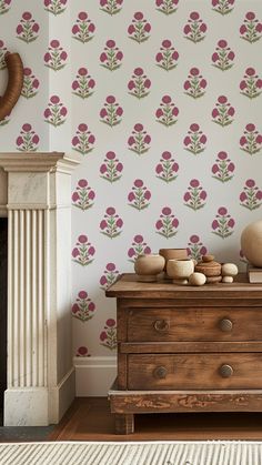 a living room scene with focus on the flower wallpaper and wooden dresser in the foreground