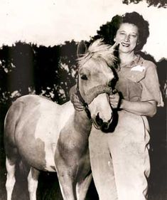 a woman standing next to a brown and white horse