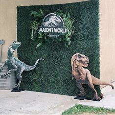 two fake dinosaurs are standing in front of a wall with the words,'dinosaur world '