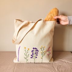 a person holding a bag with flowers on it and a piece of bread in the other hand