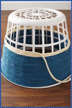 a blue and white birdcage sitting on top of a wooden floor next to a rope