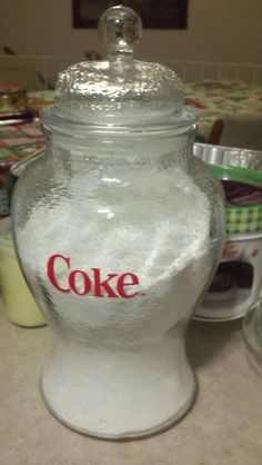 a glass jar filled with coke on top of a counter