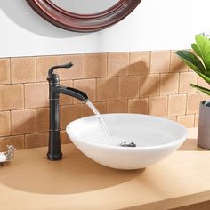 a white bowl sink sitting on top of a wooden counter next to a round mirror