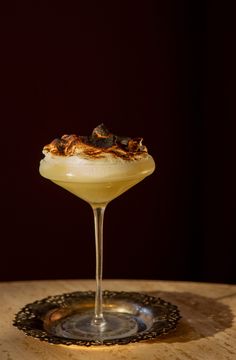 a drink in a glass sitting on top of a wooden table