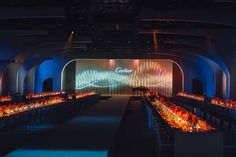 a large banquet hall filled with lots of tables covered in orange and blue cloths