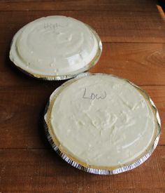 two pies sitting on top of a wooden table next to each other with writing on them