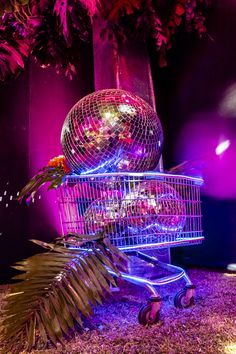 a disco ball sitting on top of a shopping cart in front of a palm tree