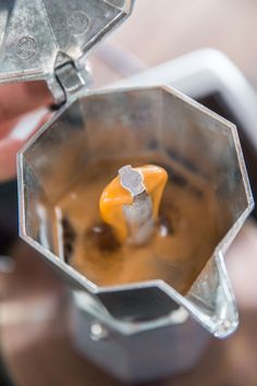 a person holding a blender filled with liquid and an orange piece of food in it