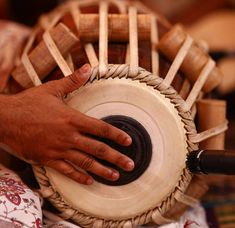 a person's hand on top of a wooden drum