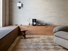 a living room with a couch, chair and speakers on the sideboard in front of a brick wall