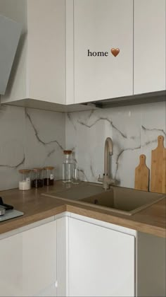 a kitchen with white cabinets and marble counter tops