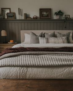 a bed with pillows and blankets on top of it in a bedroom next to a wooden floor