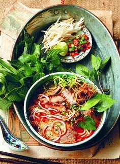 two bowls filled with food sitting on top of a wooden table next to utensils