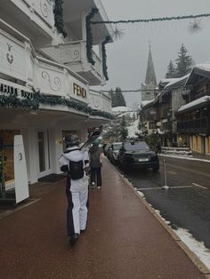 a man walking down the street in front of a building with christmas decorations on it