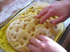 two hands reaching for an uncooked pizza dough