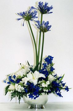 a white vase filled with blue and white flowers