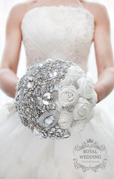 a bridal bouquet with white roses and brooches is held by the bride